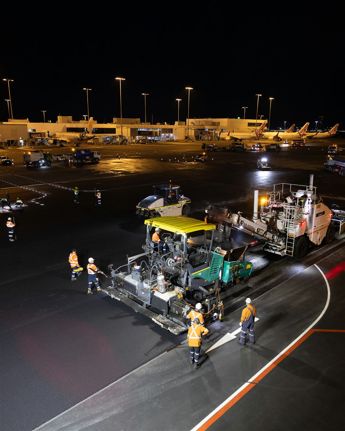 Airport construction equipment on a tarmac at night.